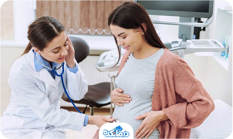 یک زن باردار که متخصص زنان گوشی پزشکی را روی شکم او گذاشته است
